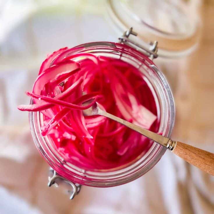 Red pickled onions in a jar with a small fork