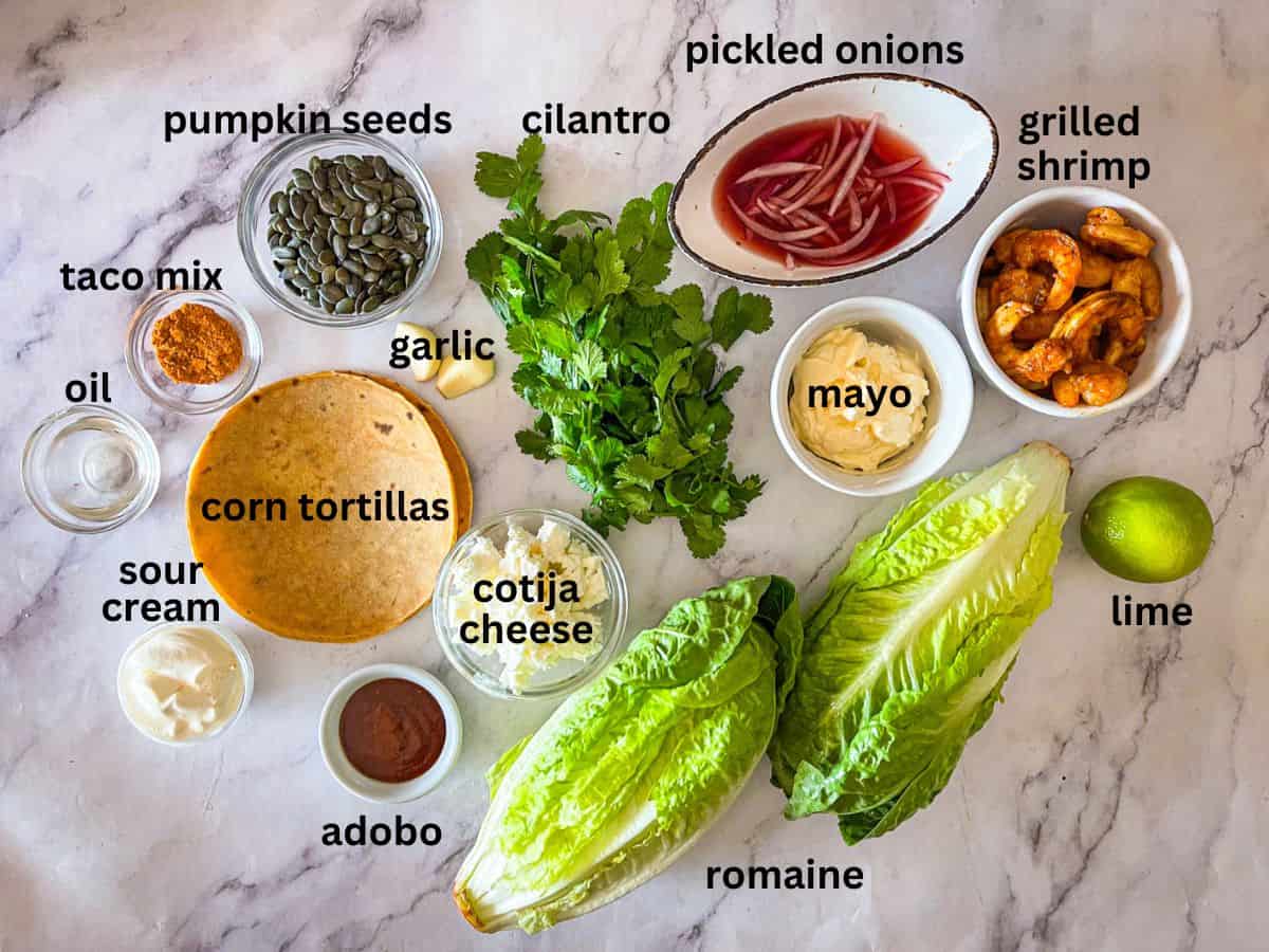 ingredients for mexican Caesar salad with shrimp laid out on a table and labeled.