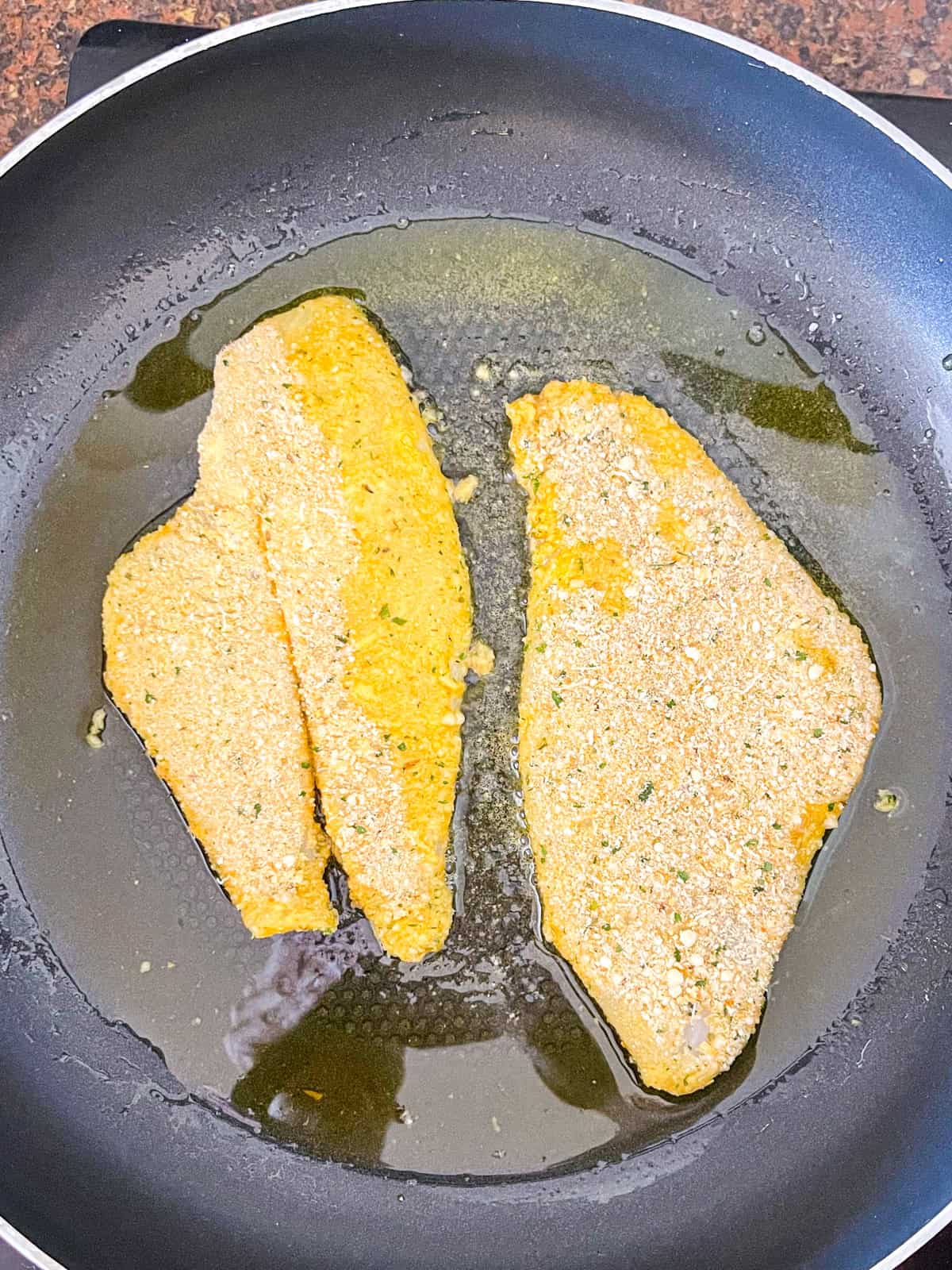 two fish fillets added to a nonstick skillet.