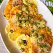 piccata sauce poured over fish fillets on a platter.