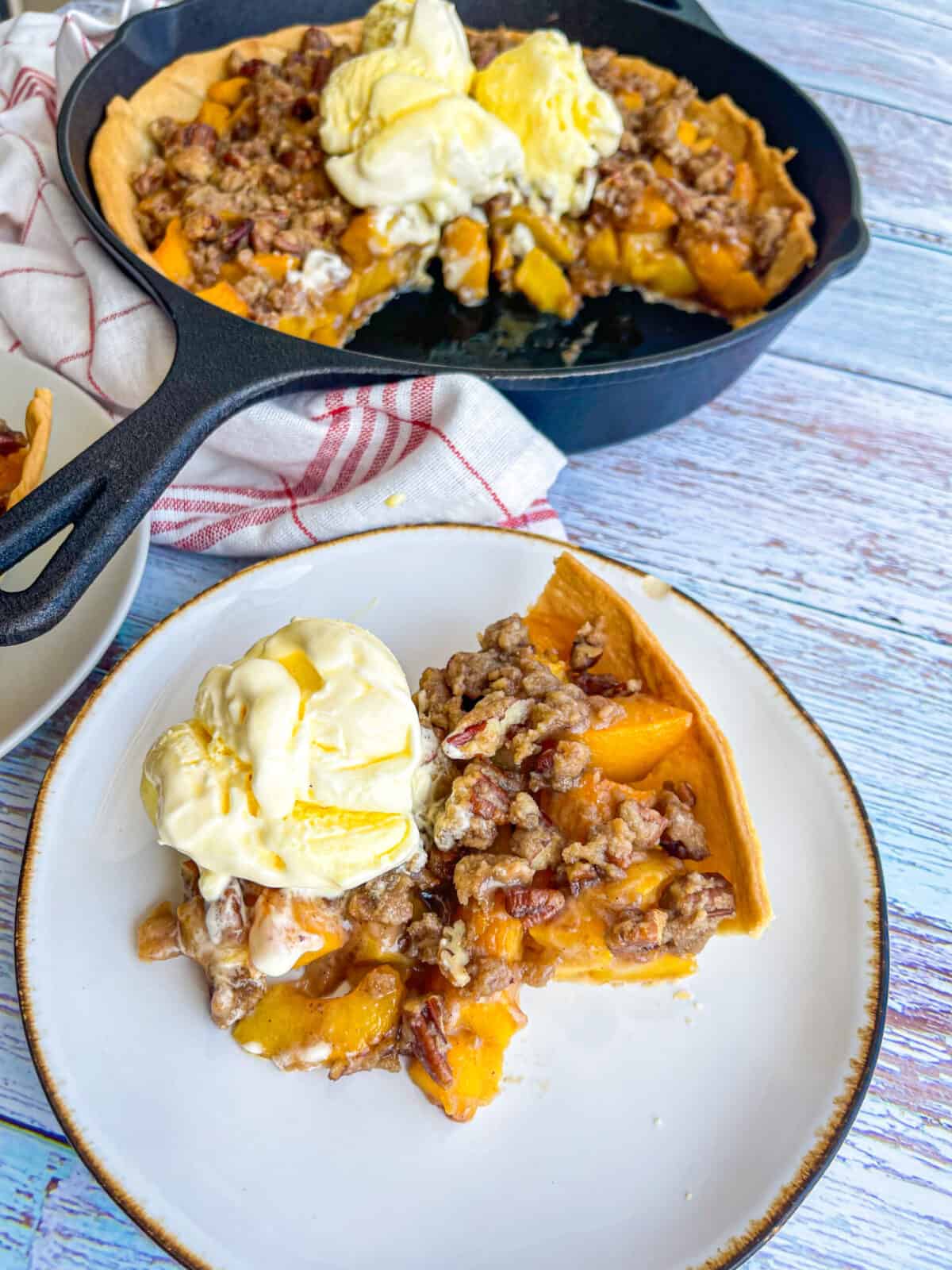 a slice of peach pie with ice cream served on a plate.