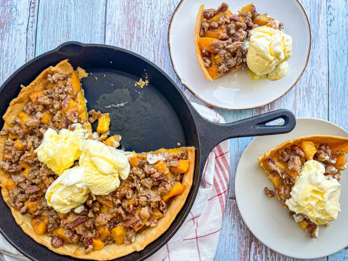 Brown Sugar Peach Crumb Pie in a skillet and on two small plates with ice cream.
