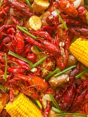 crawfish boil spread over newspapers garnished with chives and orange wedges.