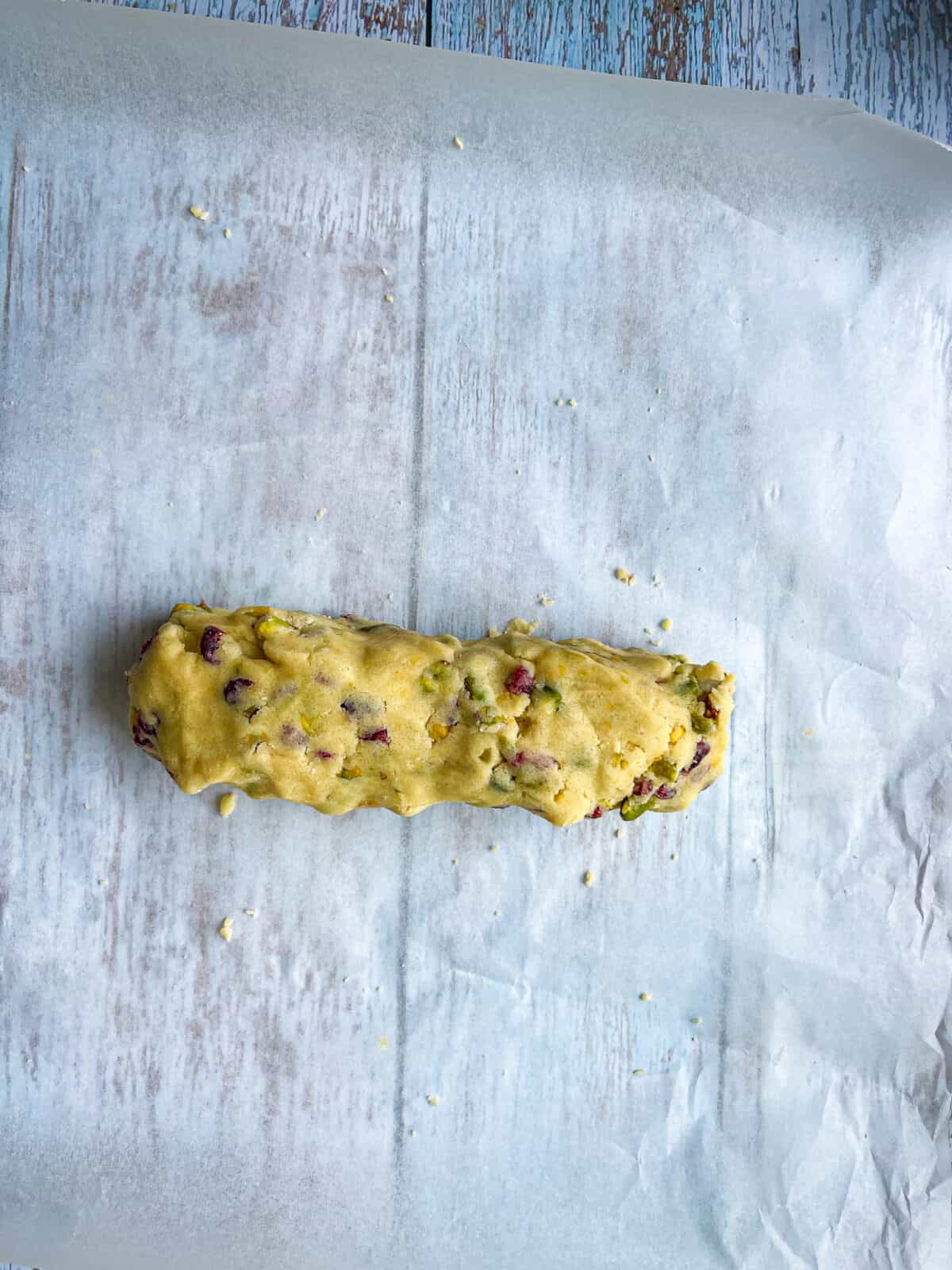 half of cookie dough shaped roughly into log on parchment paper