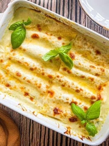 casserole dish of ricotta, spinach and shrimp stuffed cannelloni in a creamy sherry sauce.
