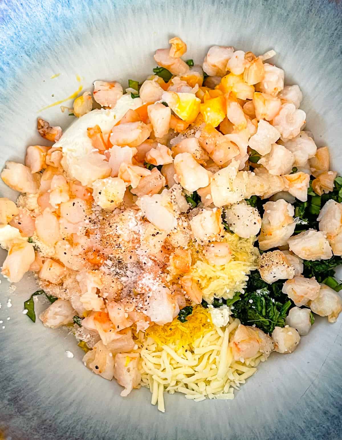 ingredients for shrimp, spinach ricotta mix added to a bowl.