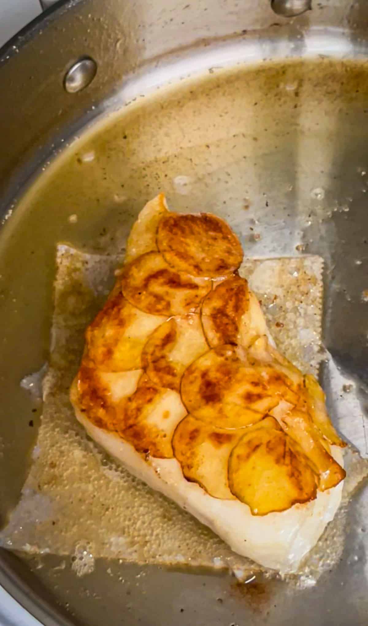 basting sea bass fillet to get a golden brown potato crust.