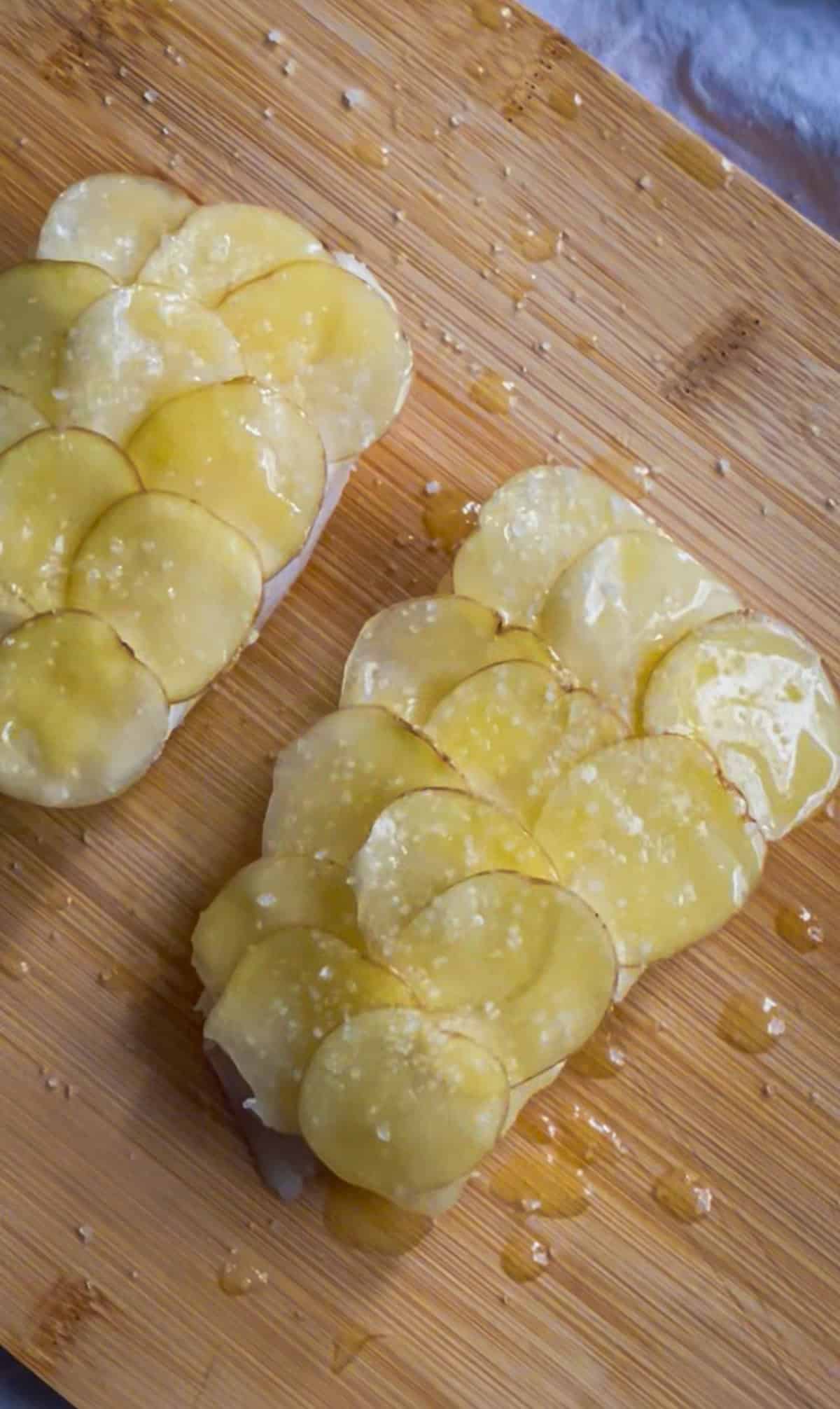 two sea bass fillets prepped with clarified butter and thin-sliced potatoes shingled over the top.
