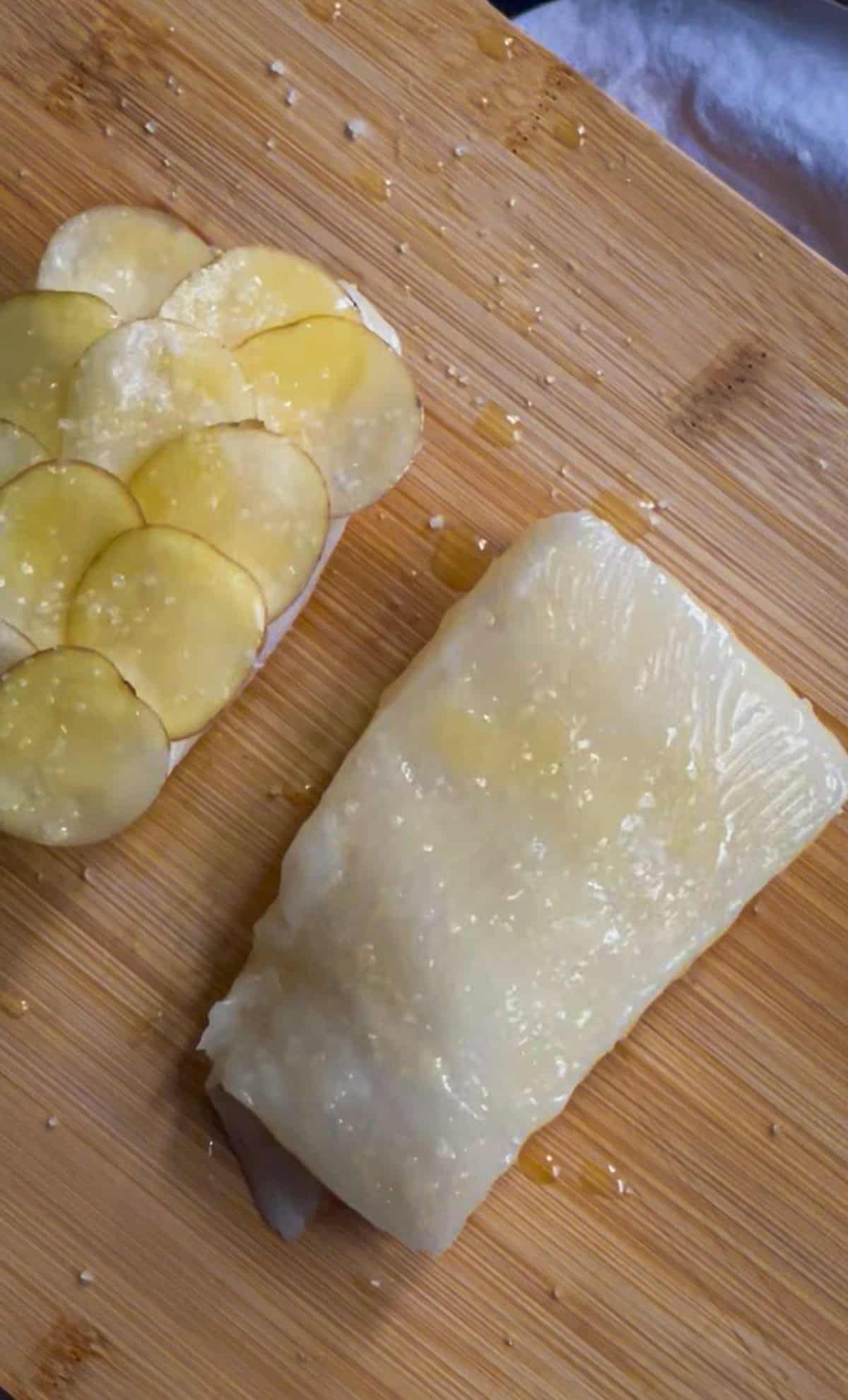 two sea bass fillets - one with potato shingles and one with butter.