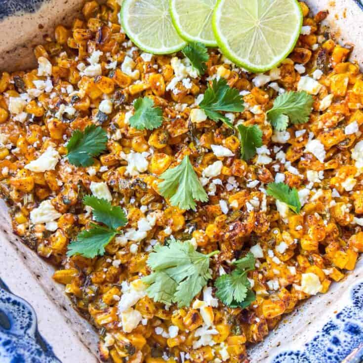 finished recipe in a blue casserole dish garnished with fresh cilantro and sliced limes
