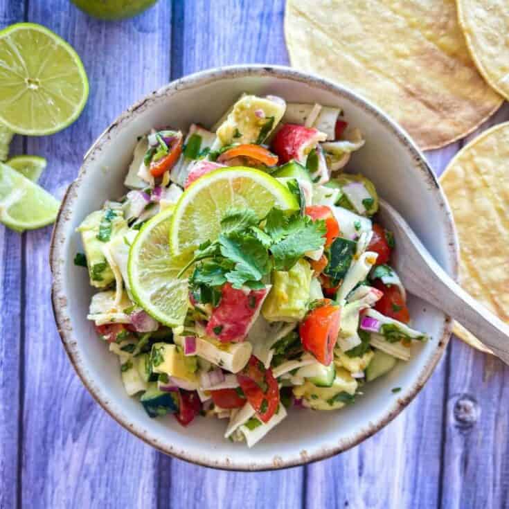 white bowl with crab ceviche garnished with limes and cilantro