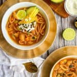 finished recipe served in two bowls and topped with lime, avocado, tortilla chips and queso fresco