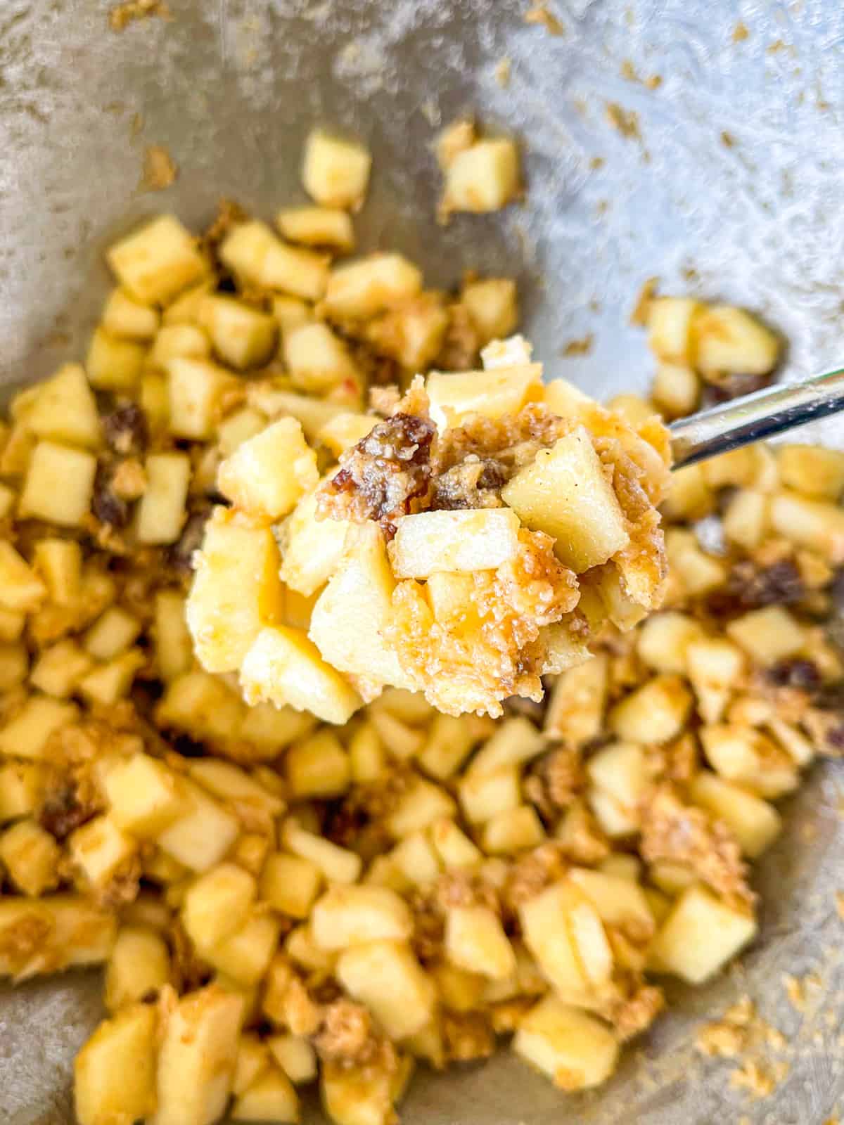 raisins, sugar and apple mix in a spoon above the bowl