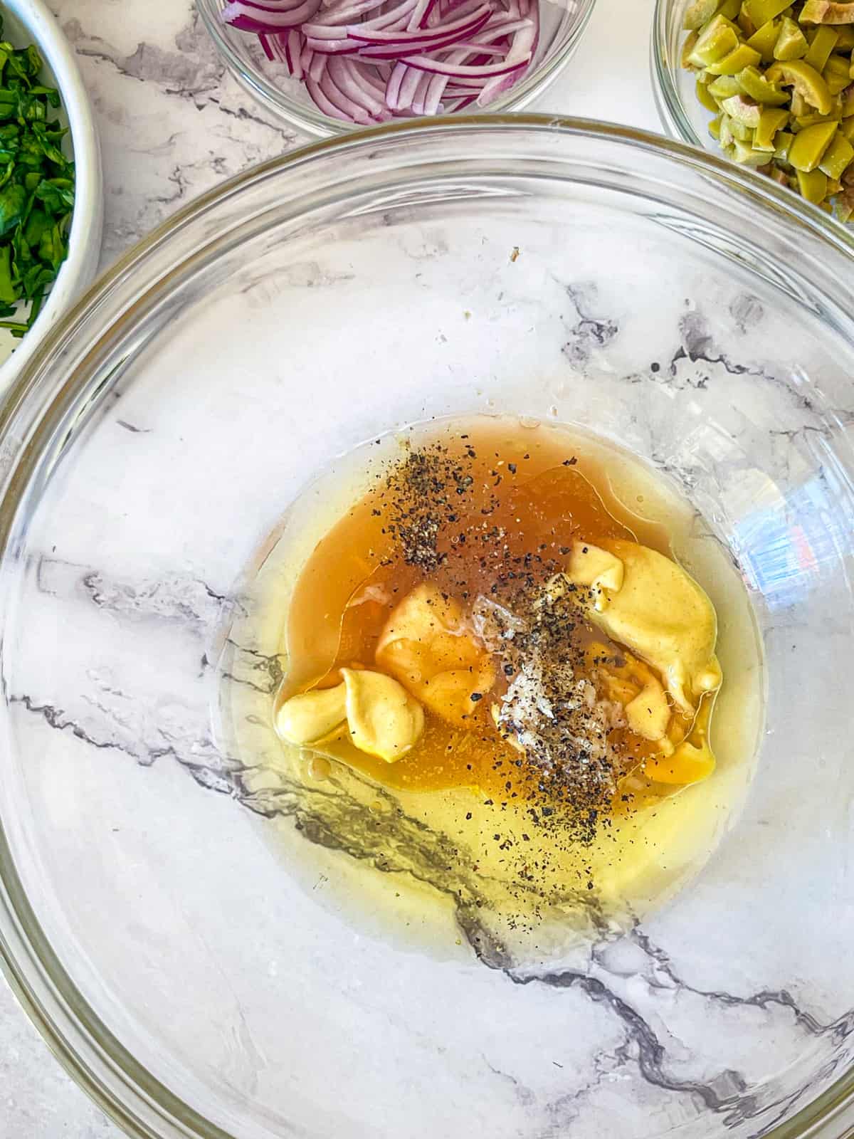 oil, vinegar, spices and mustard mixed in a bowl