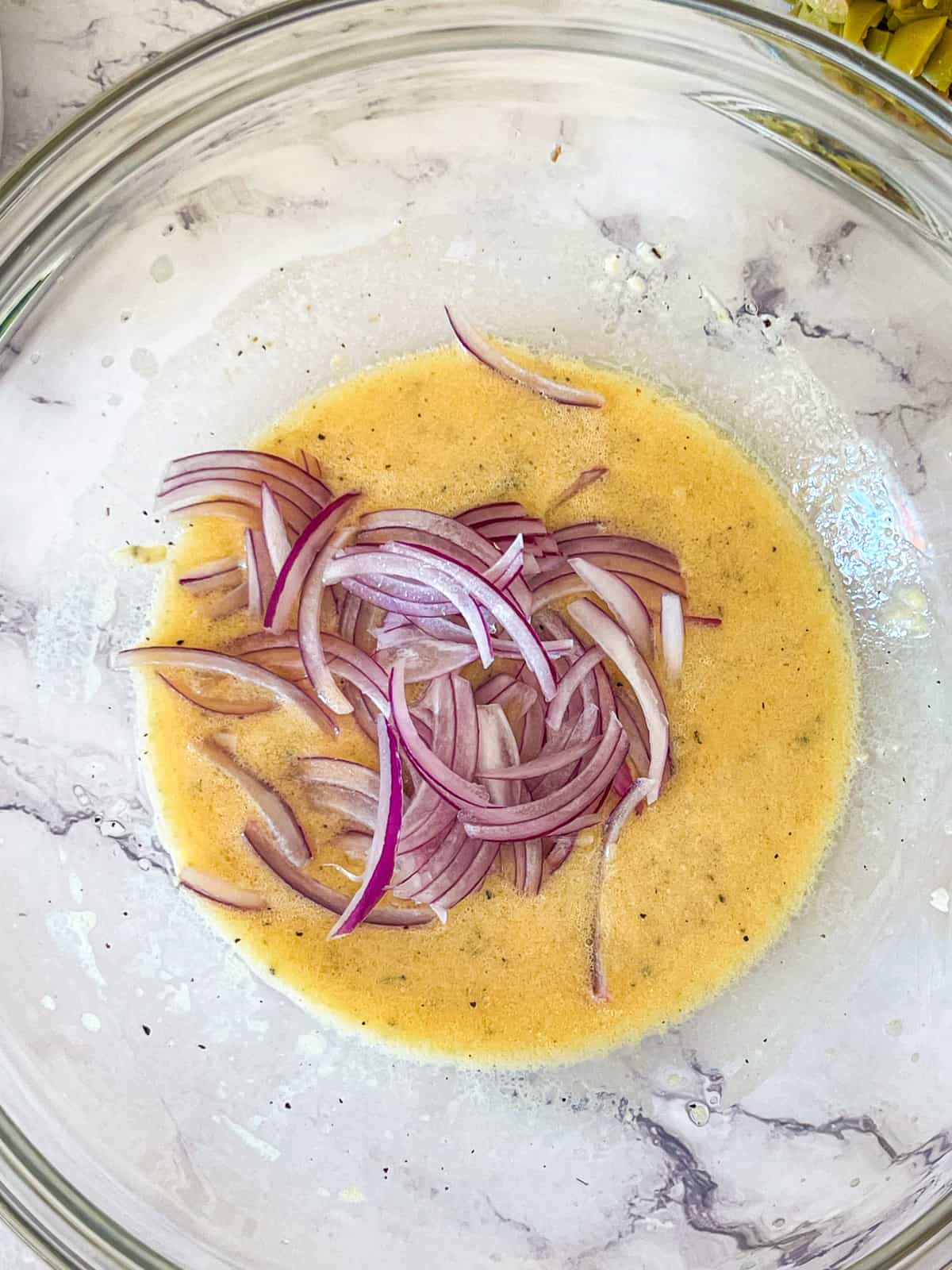 thin sliced red onions added to vinaigrette