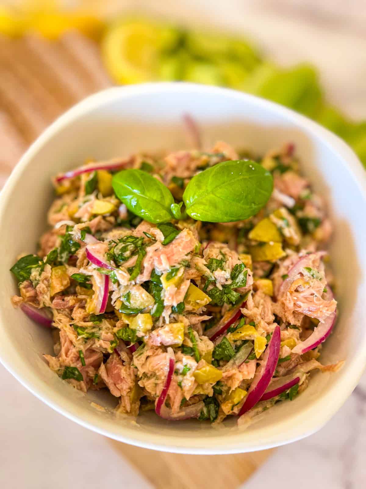 Mediterranean tuna salad in a bowl garnished with fresh basil leaves