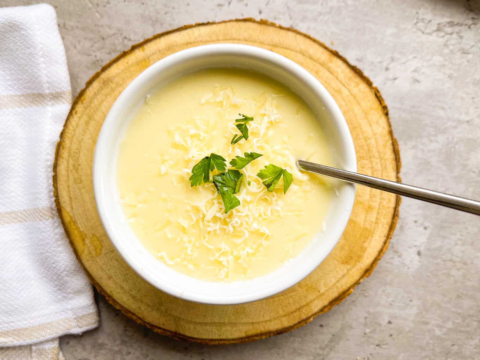 Parmesan cream sauce in a bowl garnished with parmesan and parsley.