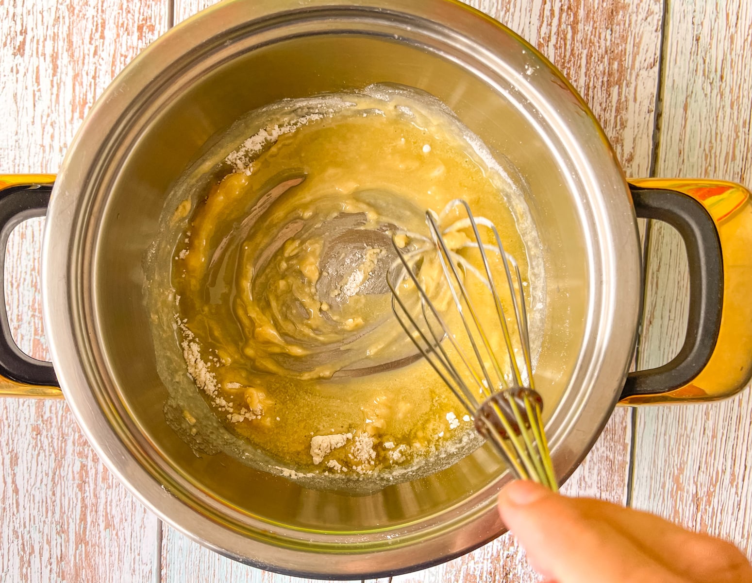 Flour being whisked into butter in a saucepan.