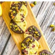 wooden board displaying chocolate-dipped pistachio cookies.