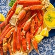 Cluster of crab legs on a tray with a bowl of melted butter sauce.