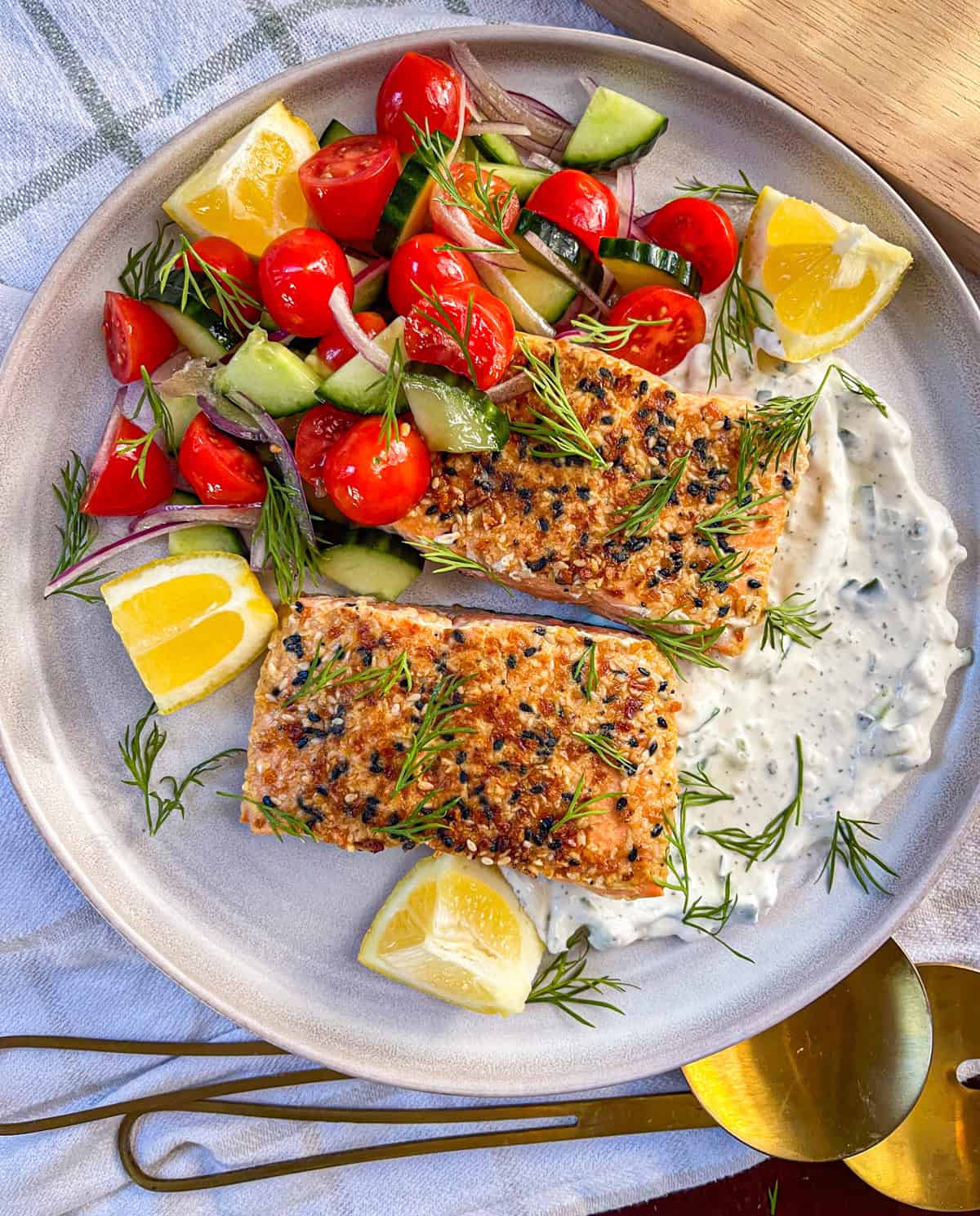 two coho salmon fillets served with sauce, veggies and herbs.