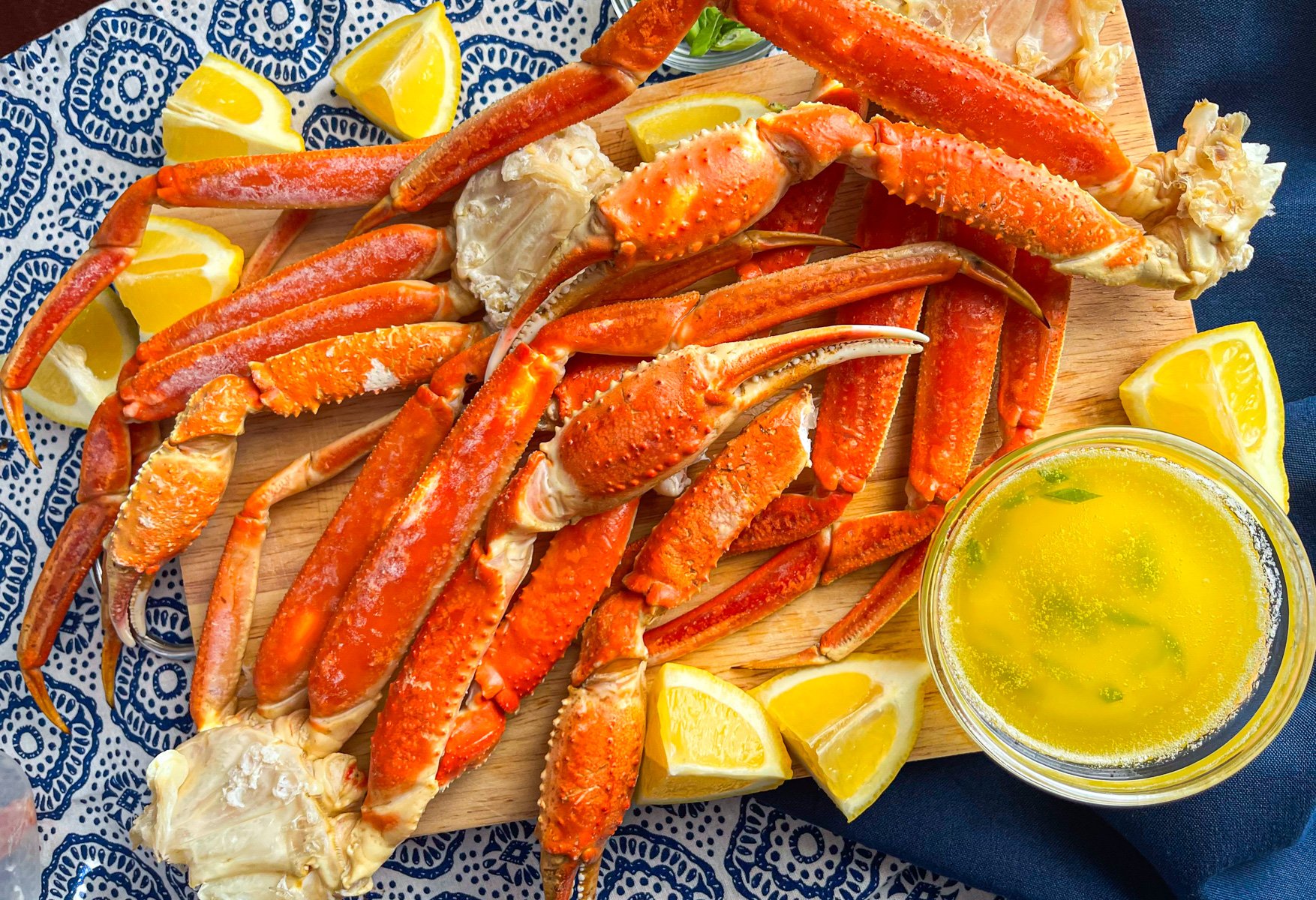 Cluster of snow crab legs on a tray with a bowl of melted butter sauce.