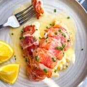 lobster with a fork on a plate in butter sauce.