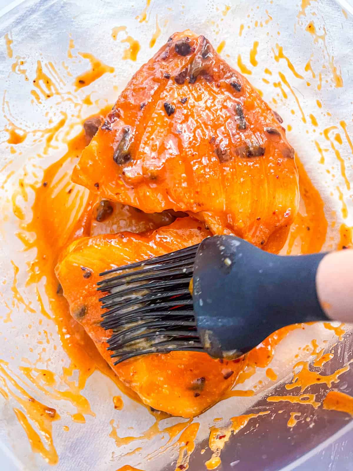 2 pieces of sea bass in a container with marinate.