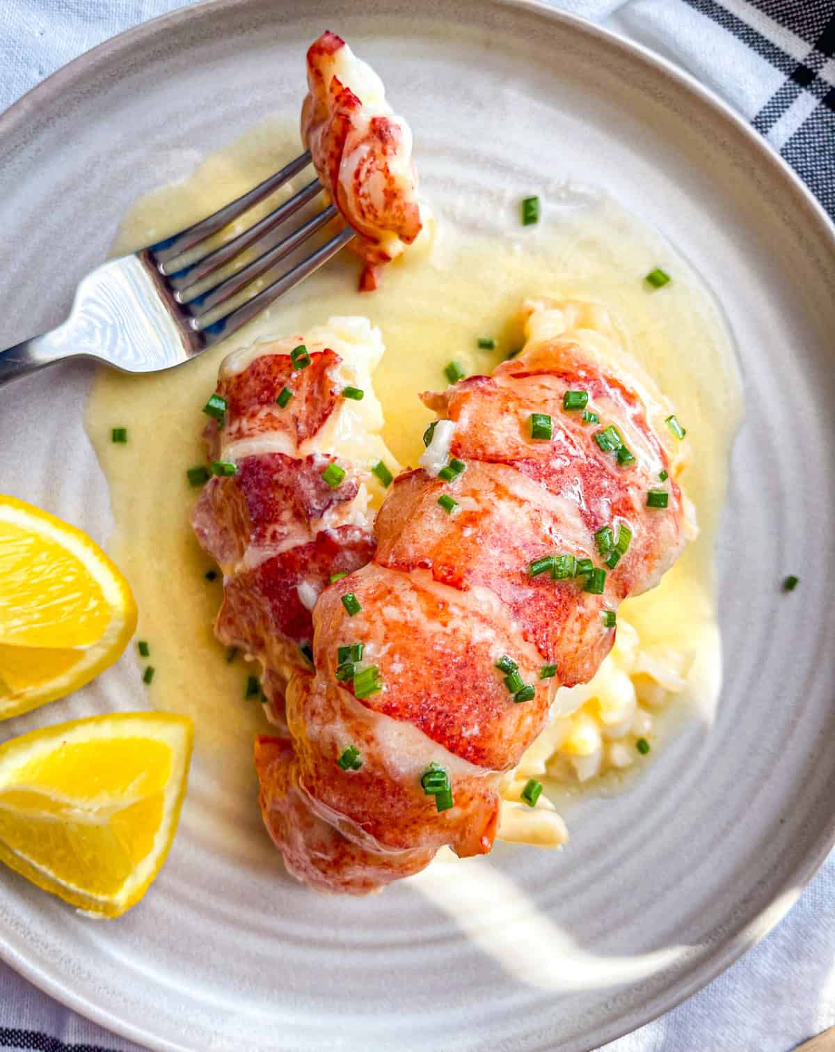 bite of poached lobster tail in butter sauce on a fork.