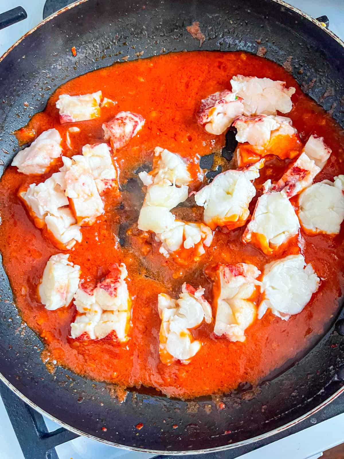 chunks of lobster in tomato sauce in a skillet