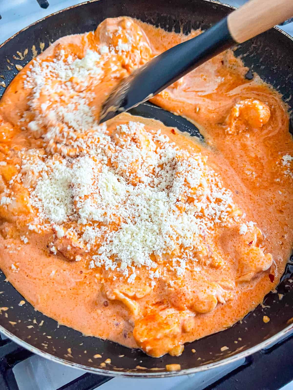 Parmesan added to creamy tomato pasta sauce with lobster.
