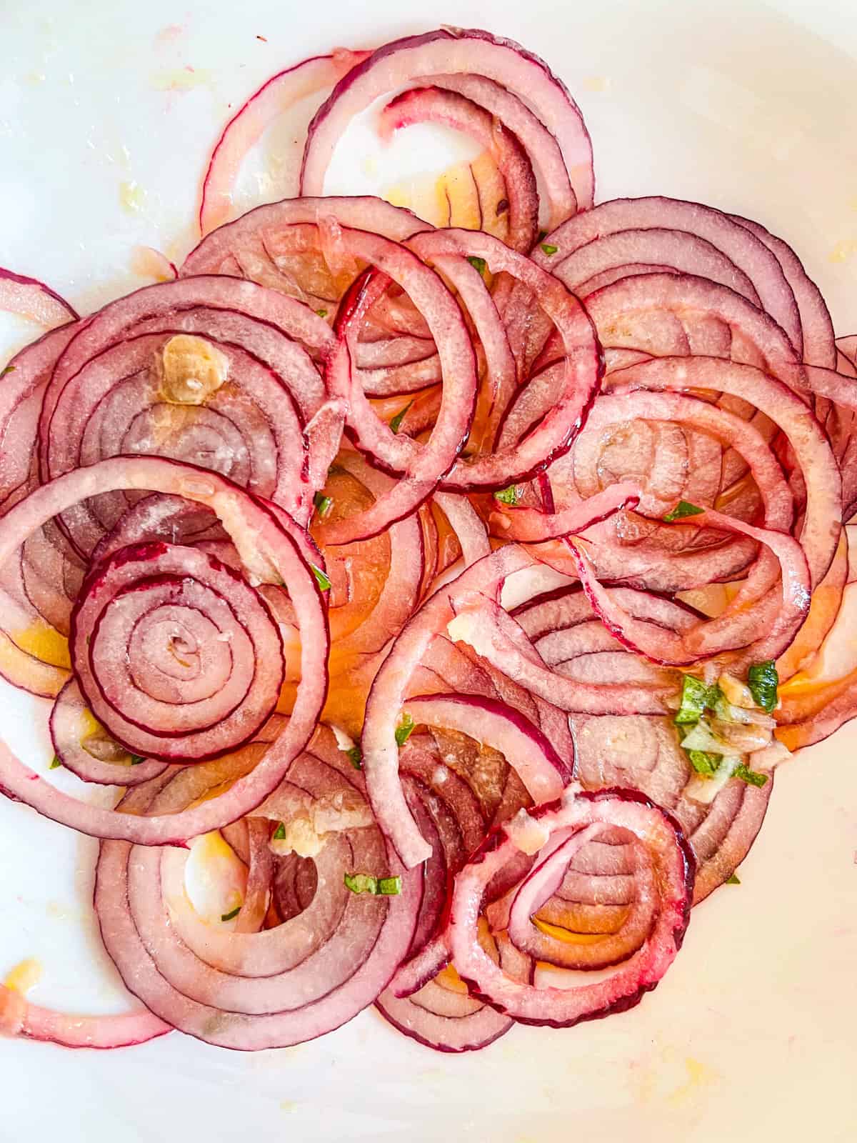 Red onion slices marinating in dressing in a bowl.