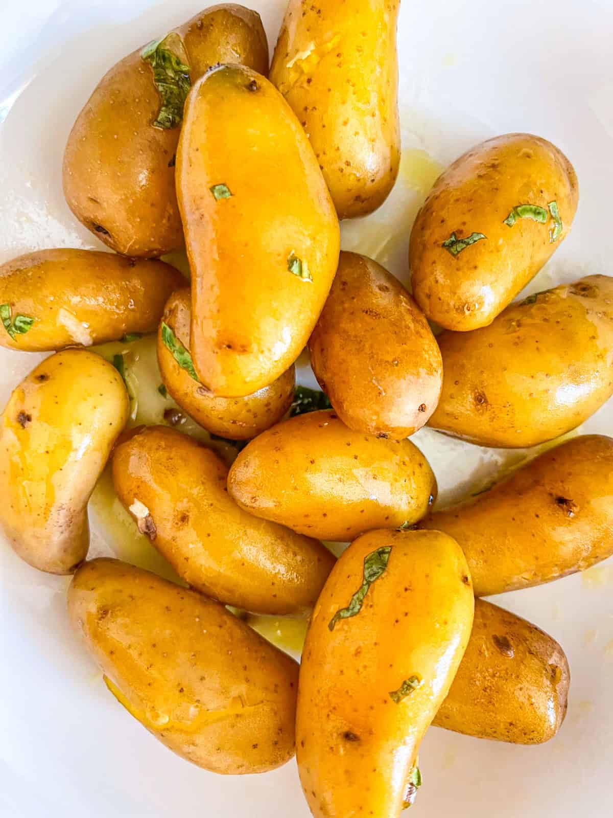 tender cooked potatoes in a bowl drizzled with lemon basil dressing.