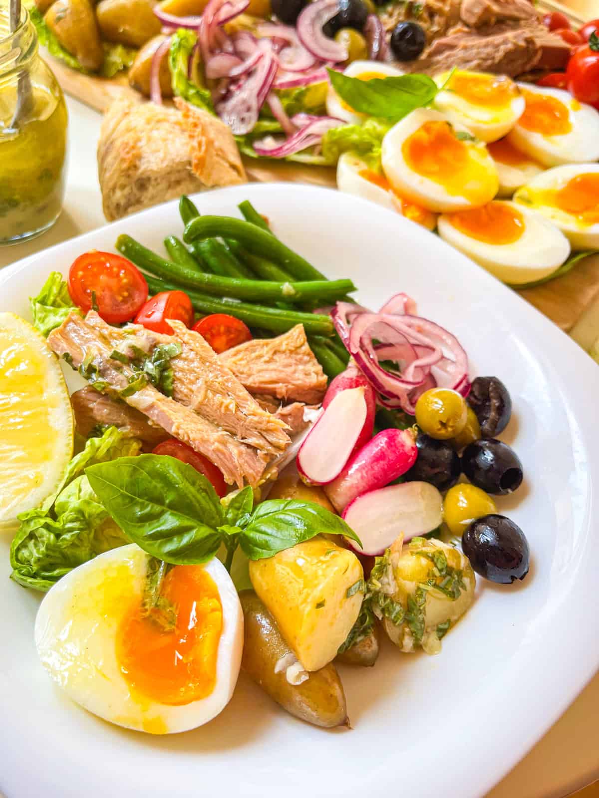 Niçoise Salad in an individual bowl garnished with fresh basil leaves.