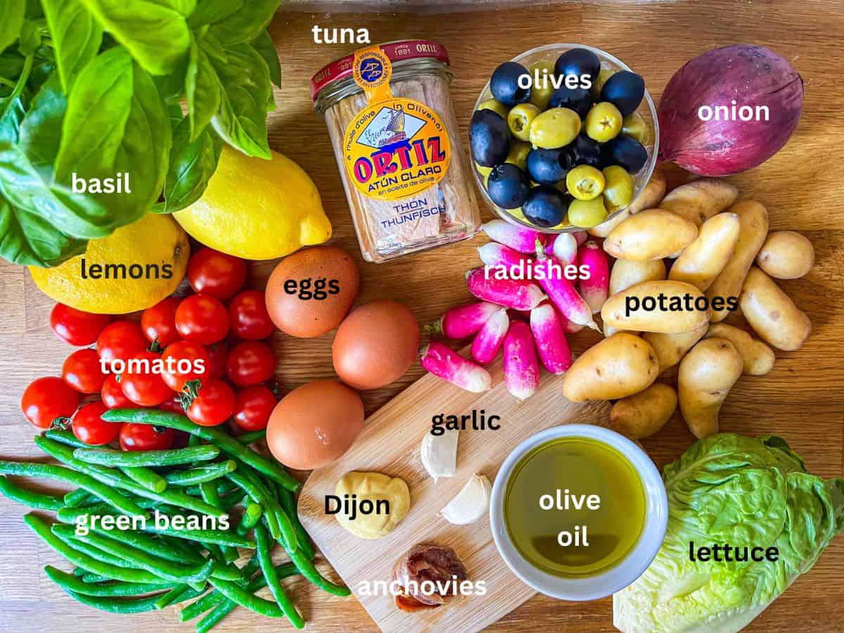 Ingredients for Nicoise Salad on a board and labeled.