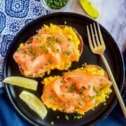 2 toast with Smoked salmon and scrambled eggs on a black plate.