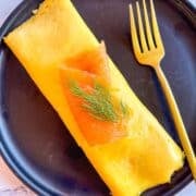 smoked salmon omellete on plate and served with a fork.