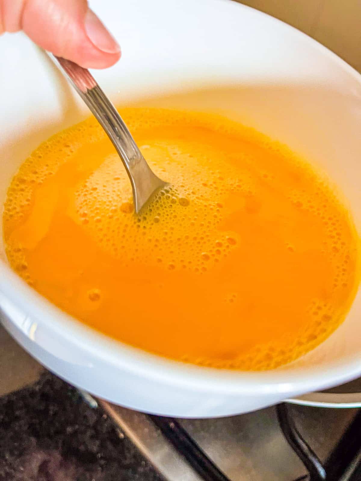 Eggs being scarmbled in a bowl.