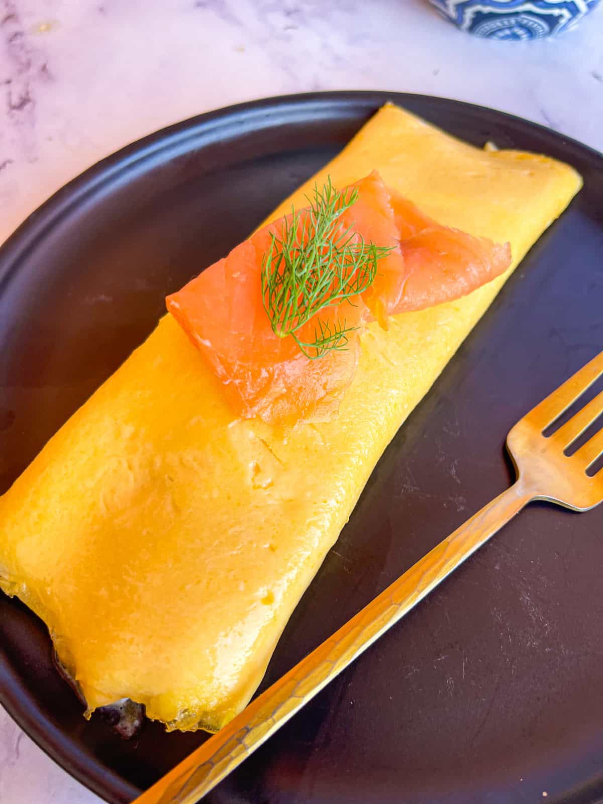 smoked salmon omellete on plate and served with a fork.