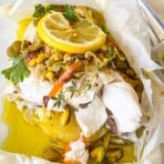 flaky baked grouper in a parchment packet with pistachios, olives and citrus.