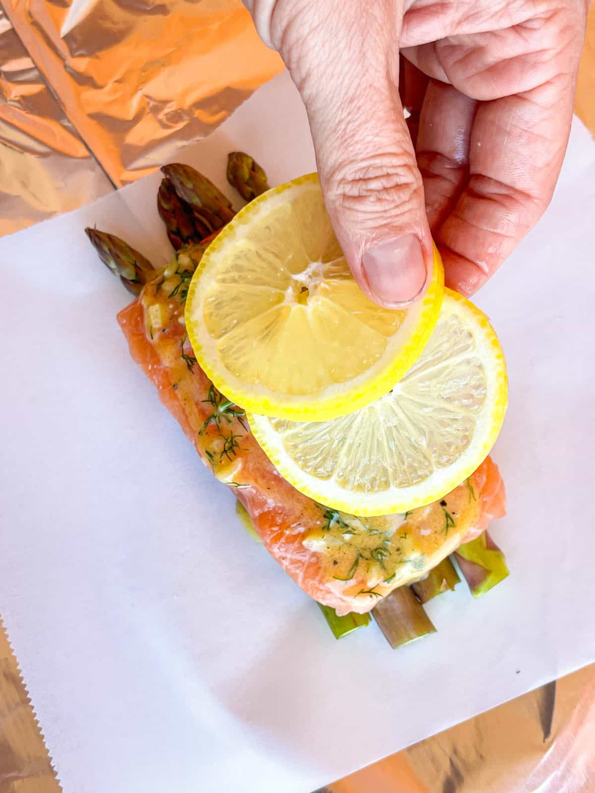 lemon slice placed over salmon and asparagus packet.