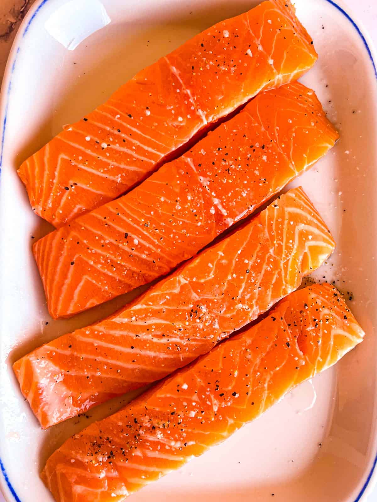 4 pieces of salmon seasoned on a plate.