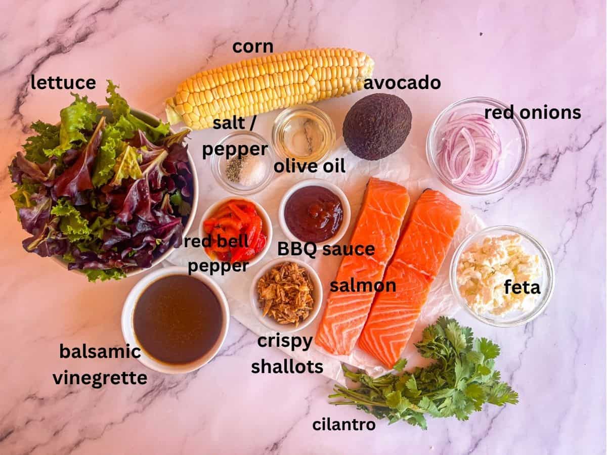 Ingredients for grilled salmon Salad on a table and labeled.