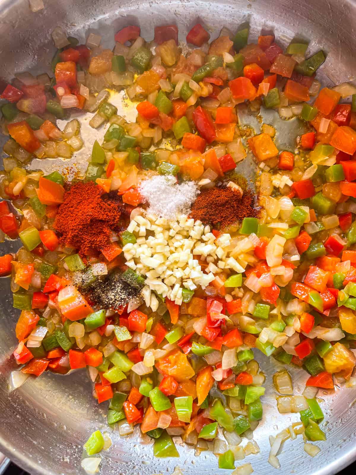 spices and garlic added to sautéed peppers, onions and tomatoes.