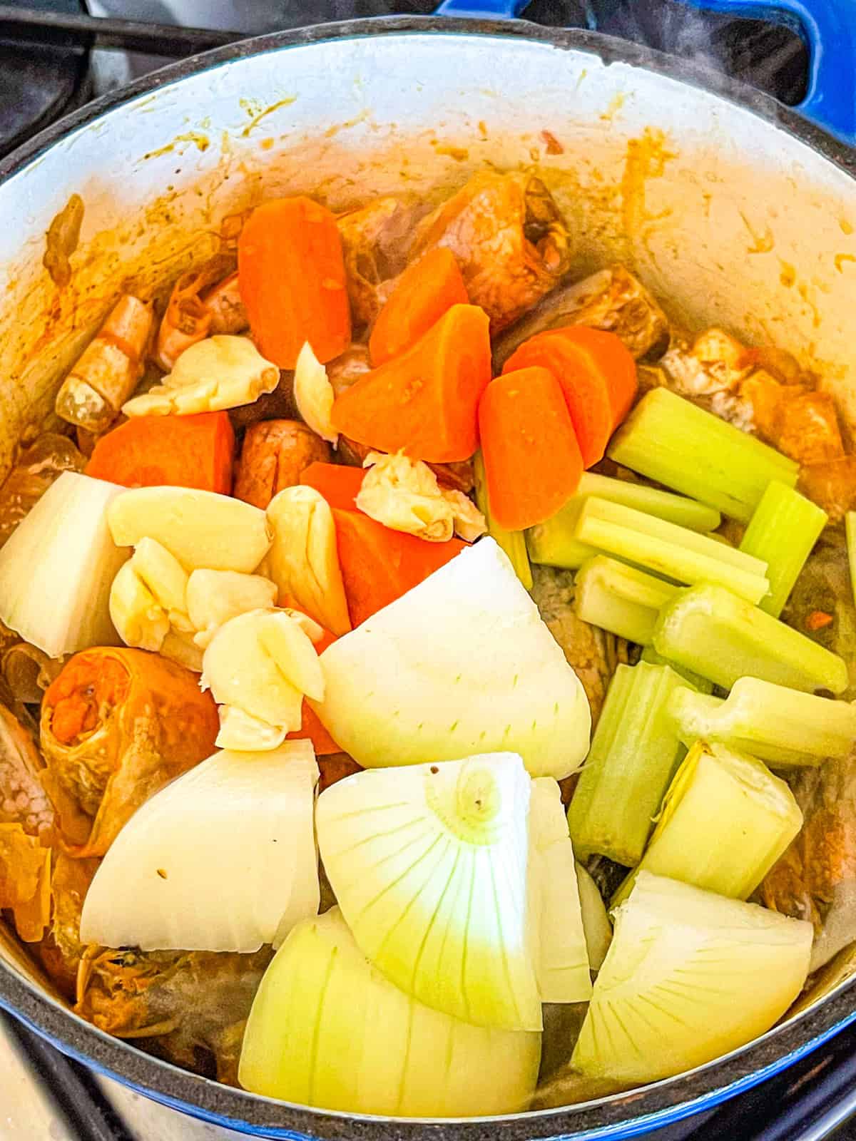 vegetables added to shrimp shells in a pot.