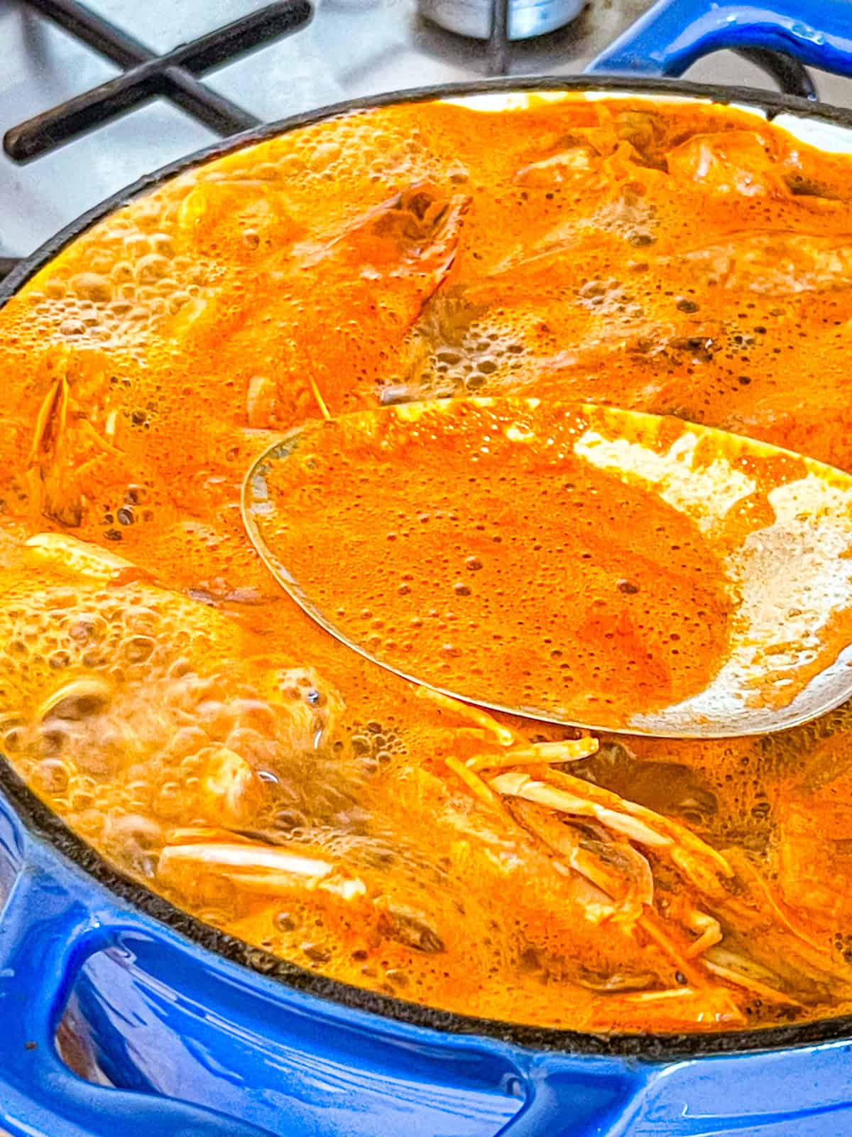 Shrimp Stock boiling in a pot with a spoon.