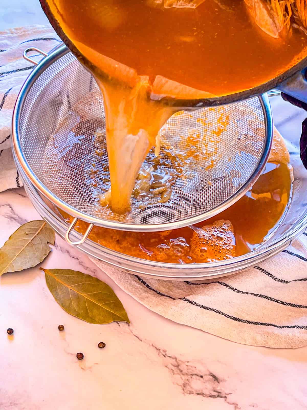 Stock poured into jar with a strainer.
