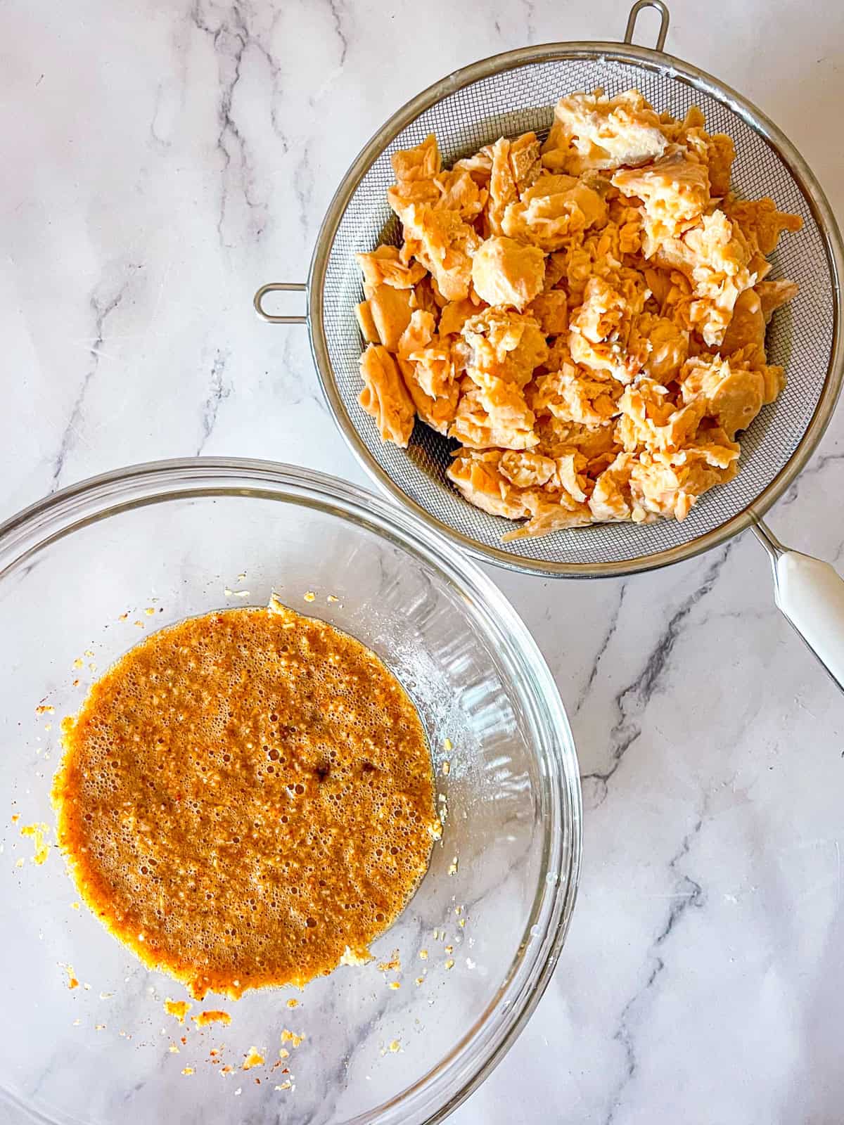 seasoned egg and panko mixture in a bowl next to canned salmon draining in a sieve.