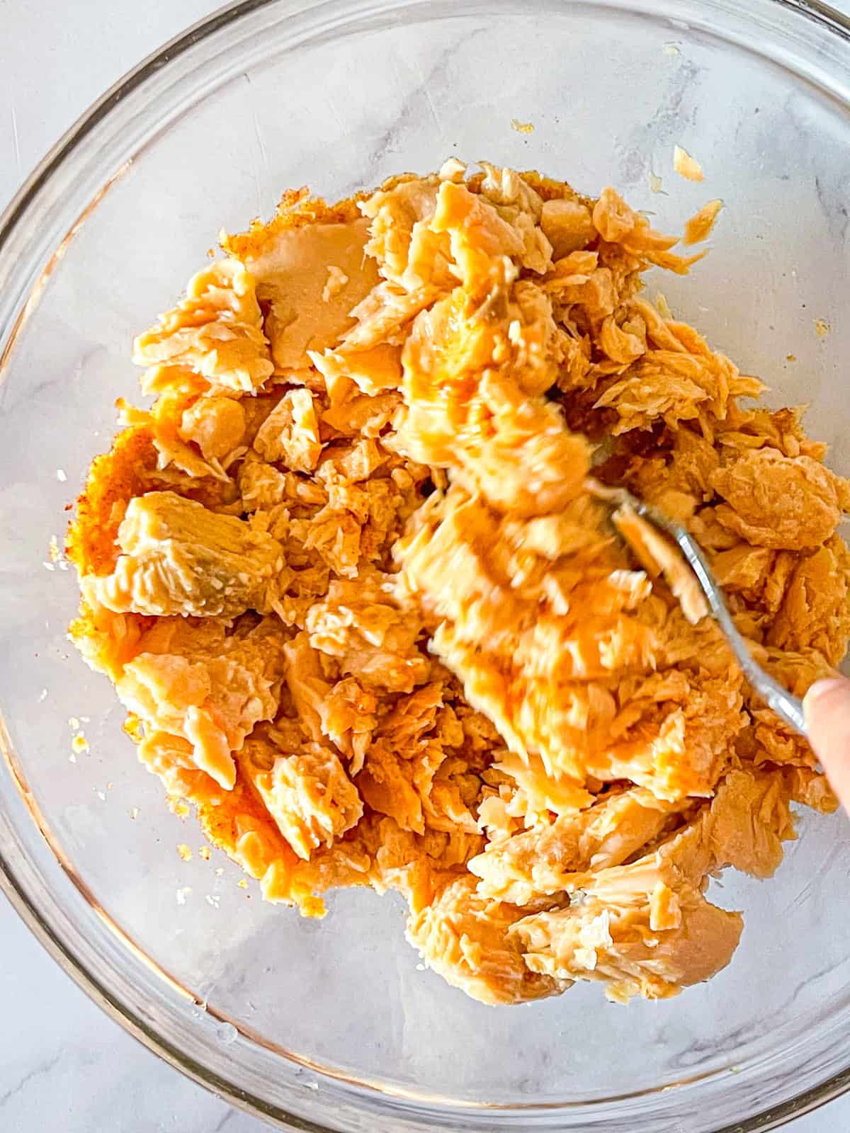 Salmon mixture for burgers in a glass bowl.