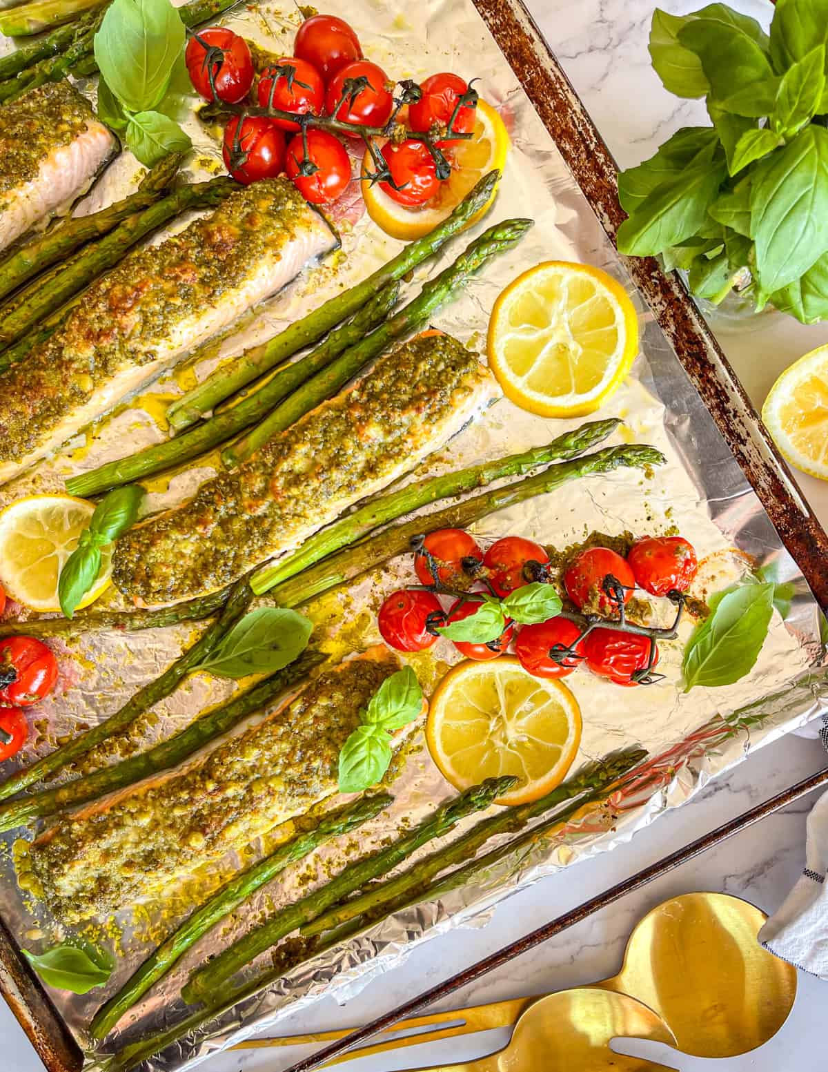 pesto salmon and veggies on a baking pan.